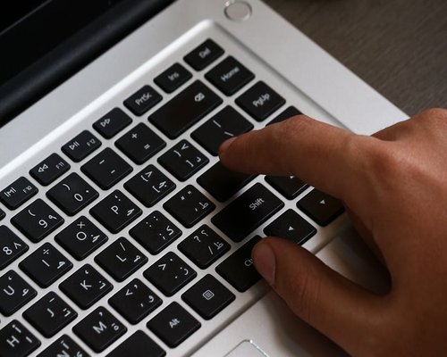Hands adjusting brightness settings on a sleek laptop keyboard