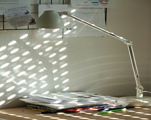 A desk lamp casting light over paperwork, avoiding shadows